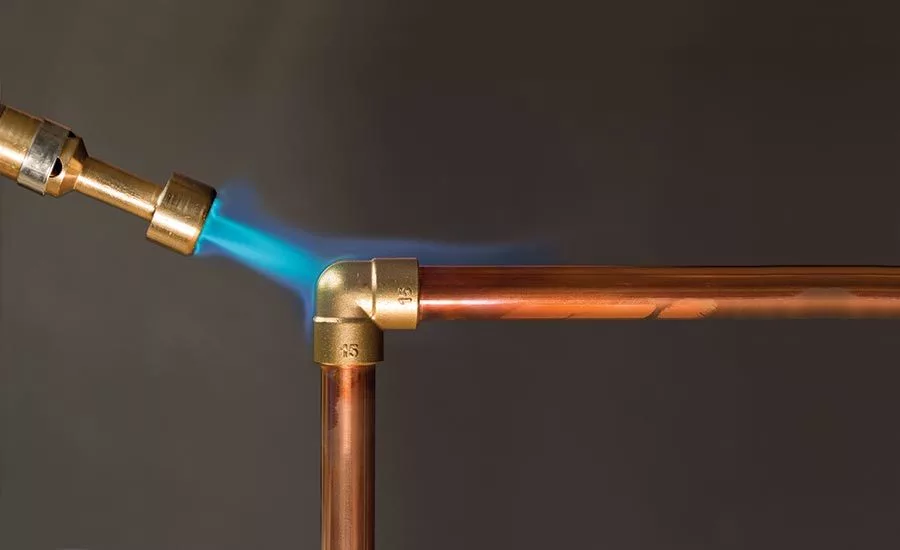 Imagen de un soplete de soldadura fuerte calentando la tubería de cobre.